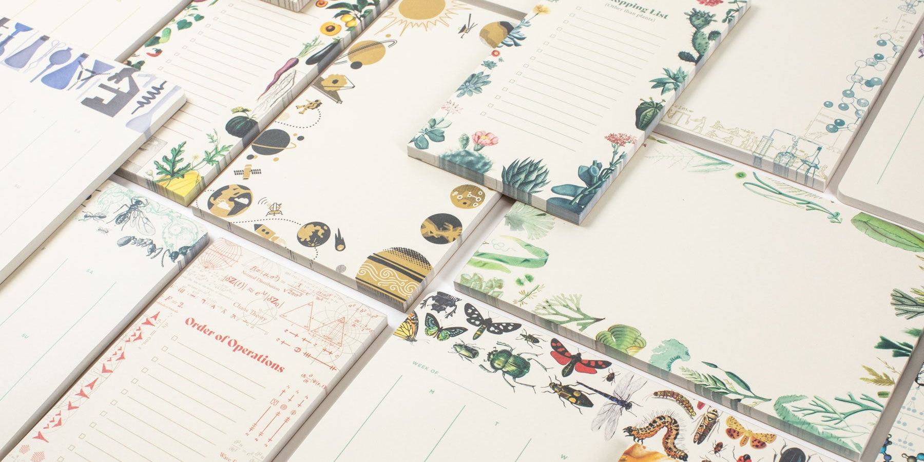A variety of illustrated paper notepads and shopping lists featuring designs such as insects, plants, space, and mathematical equations.