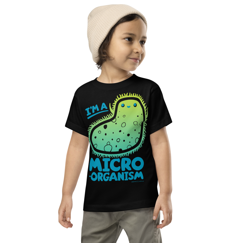 A child wearing a beige beanie and a black T-shirt with a cartoon microorganism and the text "I'm a Micro Organism.